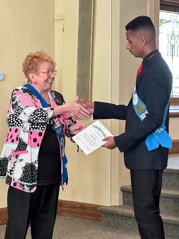 Dr. Lahr-Well congratulates an older male student with a certificate of advancement and achievement.