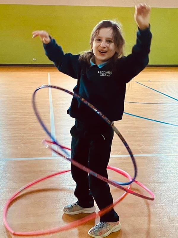 A young female Lahr-Well Academy Student tries hula hoops during recess.