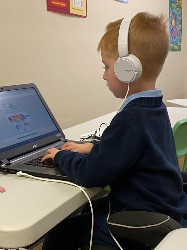 A young male student at Lahr-Well Academy uses a laptop for typing lessons.